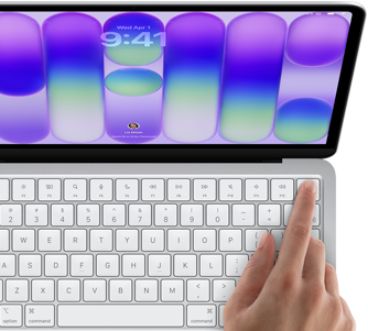 MacBook Neo w kolorze srebrnym z widocznym ekranem logowania i palcem osoby używającej czytnika Touch ID w prawym górnym rogu klawiatury